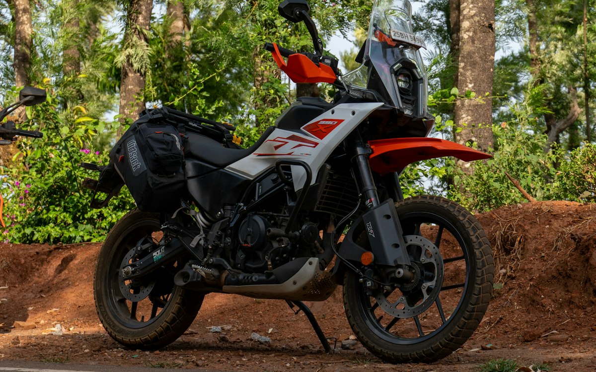 Moto trail blanche et orange stationnée sur un chemin de terre